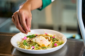 Food decoration by chef for traditional salad with fire egg with special source.