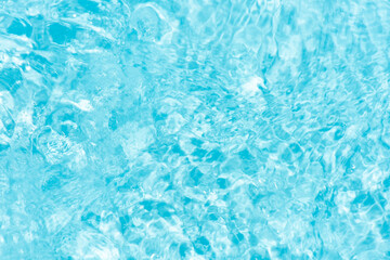 Blue water with ripples on the surface. Defocus blurred transparent blue colored clear calm water surface texture with splashes and bubbles. Water waves with shining pattern texture background.