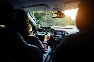 A woman holding the steering wheel tightly and driving a car. Traveling by car