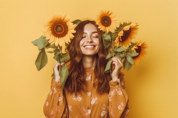 A woman holding sunflowers in front of her face