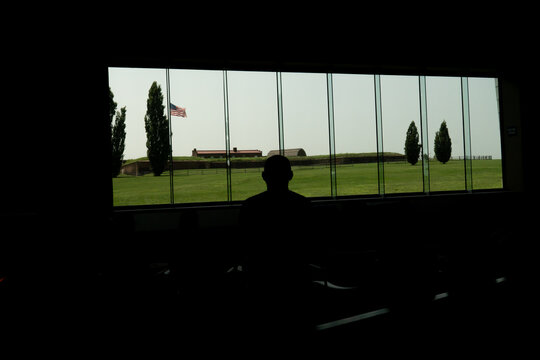 Baltimore, MD US - July 26, 2023: A military veteran stands and faces the flag at Fort McHenry National Monument and Historic Shrine, seen from inside the visitor center's theatre after a film plays