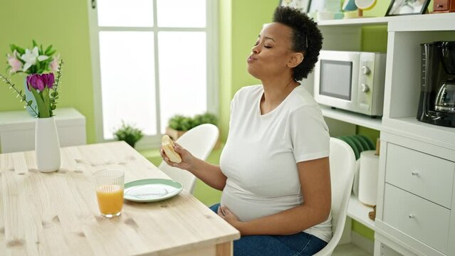 Young pregnant woman having breakfast sitting on table at dinning room