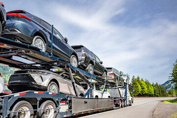 Powerful big rig car hauler semi truck transporting cars on the two level semi trailer with...