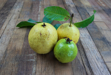 Fresh guava with green leaves on wooden background. Texture of wood and guava leaves.
