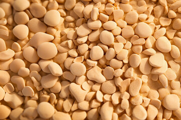 Small tan pebbles and stones in the sand, tan sand background, closeup of beach pebbles and rocks, fun sunny background made with Generative AI