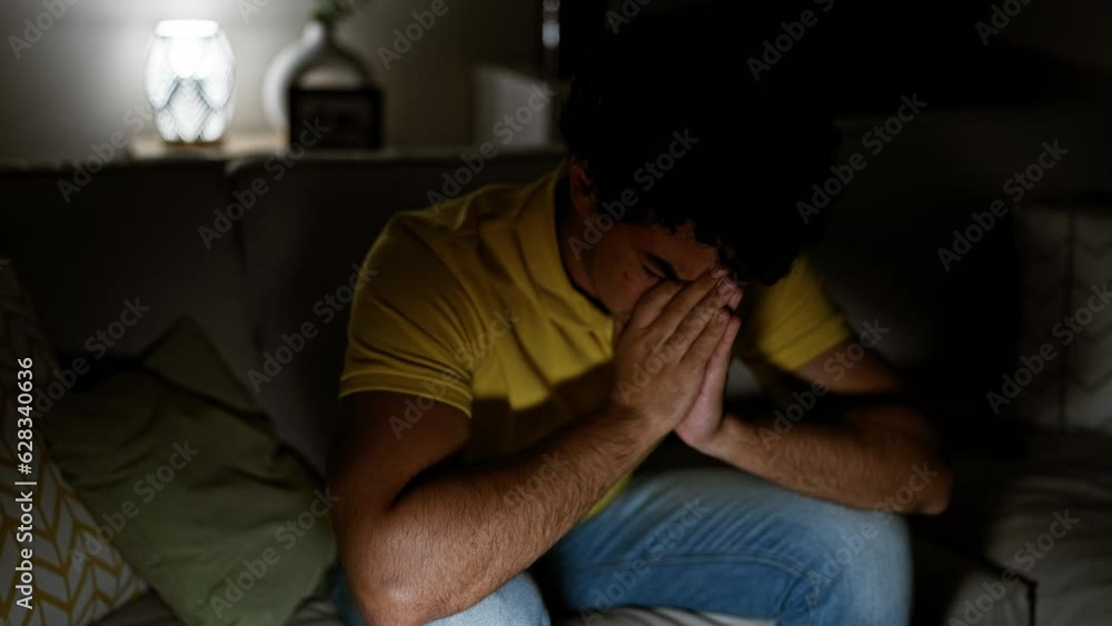 Sticker Young latin man stressed sitting on sofa crying at home