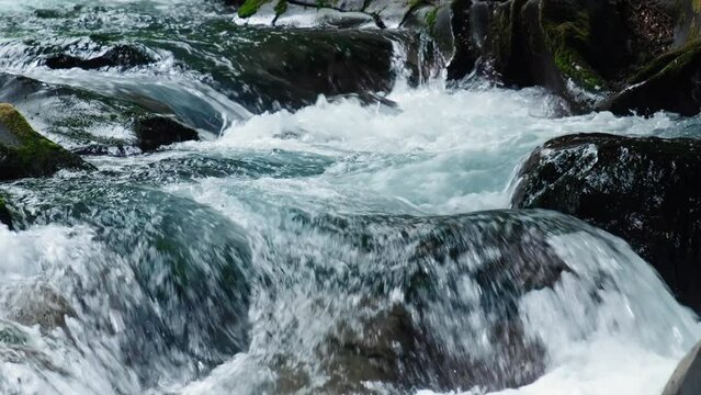 Slow motion of abundant stream of water flowing in a mountain river.