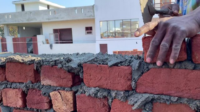Jammu, Jammu and kashmir India 19 February 2021. Mason Man is  working at the construction site of bricks. The man loads bricks on a wall