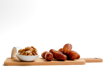 fresh dates with walnuts on a wooden board with a white background
