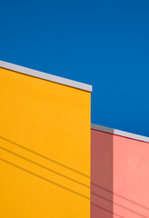 Minimal architecture background of colorful vintage building wall against blue clear sky in low...