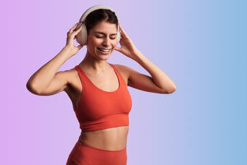 Smiling sportswoman listening to music in studio while adjusting headphones