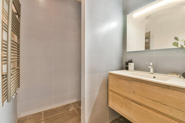 a modern bathroom with wooden cabinets and white tiles on the wall behind it is a large mirror above the sink