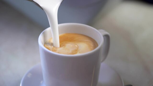 manos preparando cafe capuchino café con leche en cafetería con maquina cafetera expreso en taza blanca vertiendo la leche espumoso con rico aroma