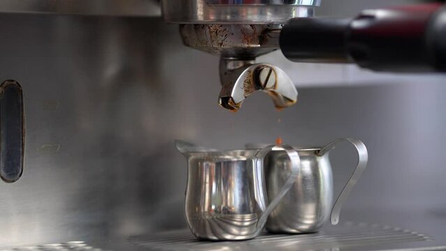 Cafeteria haciendo una preparación de café expreso o americano de maquina cafetera en tazas de acero inoxidable rico aroma y delicioso sabor cafetera goteando cafe al terminar de servir
