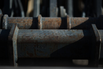 Rusted, heavily worn pistons power a piece of heavy machinery at a construction site.