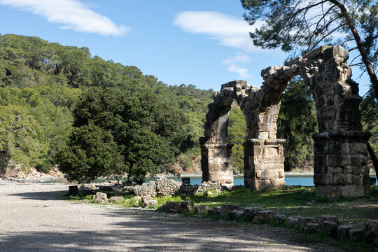 Huge stone arch in the middle of ancient ruins and ruined walls. The remains of ancient Lycia civilization, Phaselis antique city in Turkey. Mediterranean landscape