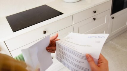 Close up of woman at home opening and reading letter about increase in mortgage rate during cost of living crisis - shot in slow motion