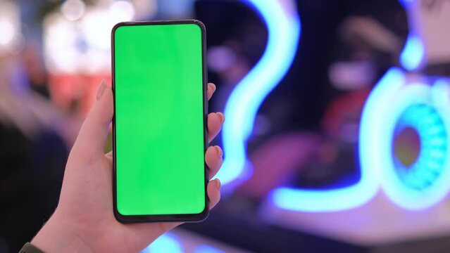 Handheld Camera: back view of brunette holding chroma key green screen smartphone watching content. Shopping online. Gadgets and contemporary people concept.