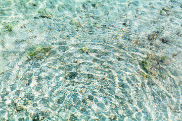 Obraz premium Sea water round waves texture, ripples water surface, concentric rings of falling drops, transparent light blue ocean water top view, clear aqua background, sun glow reflection, tropical island beach