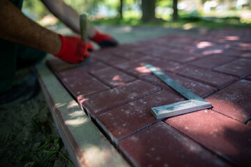 The protractor lies on the paving stones and the worker lays the pavement.