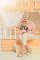 Portrait of happy senior woman at home with flowers
