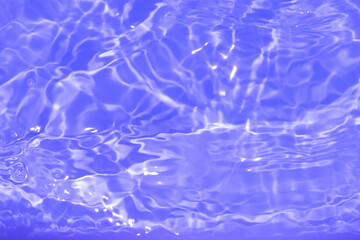 Purple water with ripples on the surface. Defocus blurred transparent pink colored clear calm water surface texture with splashes and bubbles. Water waves with shining pattern texture background.