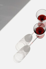 Still life with colored glass glasses of dry red wine with sunlight shadows, summer flat lay....