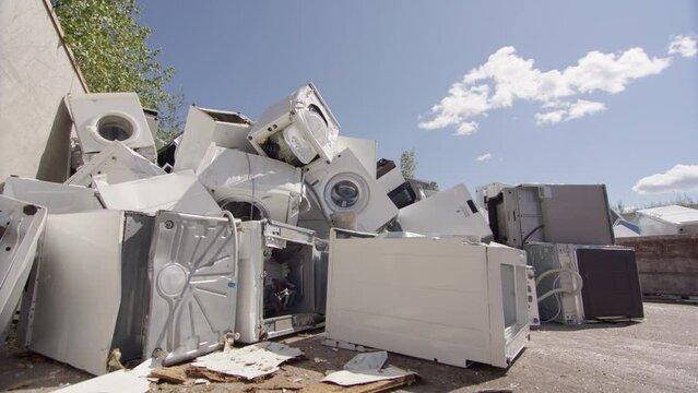Dramatic low angle slider of discarded washing machines and appliances at dump