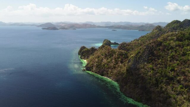 Cinematic aerial footage of the cliffs of Palawan while flying forward revealing beautiful beaches and lagoons with boats in focus, Philippines, Asia, Drone