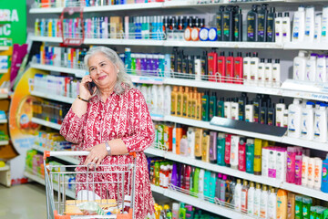 Senior woman talking on smartphone at grocery shop.