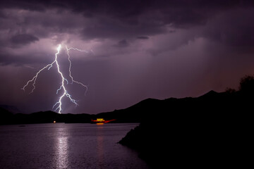 Lightning bolts striking at Lake Mead Nevada with a houseboat in the distance