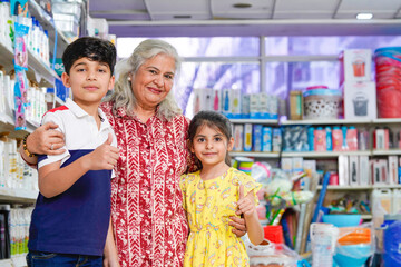 Little girl and boy showing thumps up with his grandmother at grocery shop.
