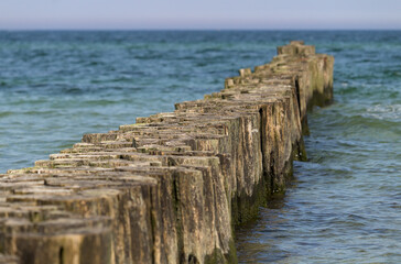 Fototapeta premium Wooden breakwater in the blue turquoise Baltic Sea with horizon and calm water. Diagonal.