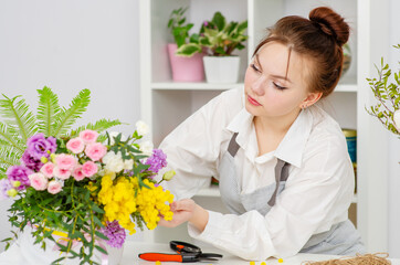 A florist girl holding a bouquet in her hands in a florist shop