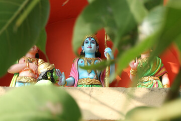 Sita, Rama, Lakshaman and Hanuman through the foliage in the foreground.