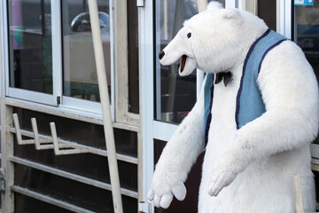 Large plush polar bear in a vest with a bow around his neck. Growth doll.