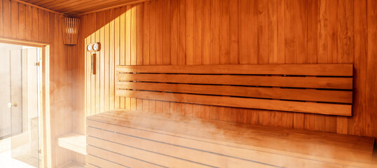 Interior of Finnish sauna, classic wooden sauna with hot steam. Russian bathroom. Relax in hot sauna with steam. Wooden interior baths, wooden benches and loungers accessories for sauna, spa complex