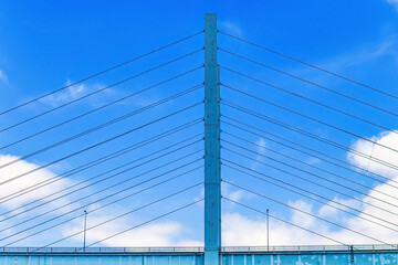 Road bridge pylon with cables at a blue sky