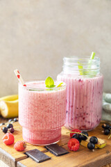 Set of fresh various delicious milkshakes or smoothies with fresh berries on a rustic background. Raspberries and black currant. Copy space.