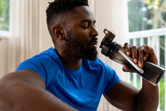 Fototapeta African american man drinking water at home