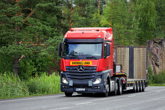 Red Mercedes-Benz Actros 2545 truck gooseneck trailer on road ready for oversize load transport. 