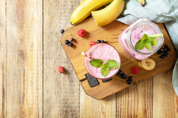 Set of fresh various delicious milkshakes or smoothies with fresh berries on a rustic background. Raspberries and black currant. View from above. Copy space.