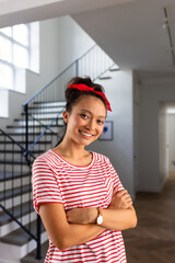 Portrait of happy asian woman with red band on head and arms crossed at home