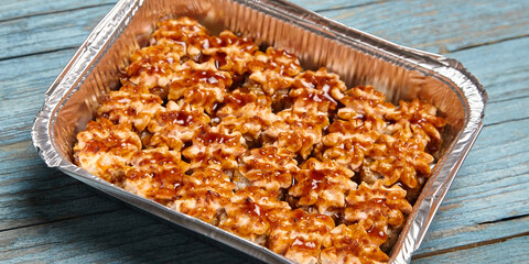 Baked sushi rolls in a baking dish on blue wooden background. Hot sushi rolls with different kind of fish and fillings. Baked sushi rolls, enticing aroma