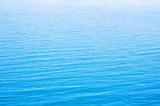 Abstract photo of Sun light reflecting or sparkling glitter on water of sea or ocean with beautiful sky blue light tone.