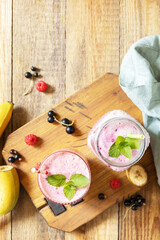 Set of fresh various delicious milkshakes or smoothies with fresh berries on a rustic background. Raspberries and black currant. View from above. Copy space.