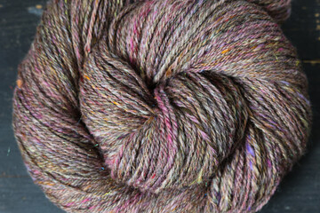 Closeup detail of colourful hand spun sheep wool merino fibres, rolled up in a yarn ball skein.