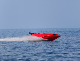 the red speedboat rushes at full speed cutting through the water