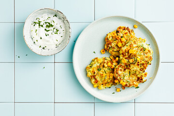 Vegetarian food. Zucchini and corn fritters with sour cream. Top view, flat lay.