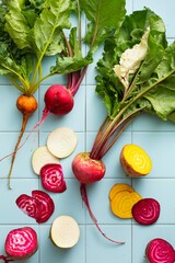 Sliced young beets of different colors, white, yellow, purple. Top view, flat lay. Tile background.